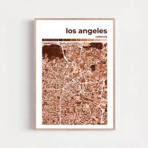 Puede incluir: Una impresión enmarcada de un mapa de Los Ángeles, California, en tonos marrones. El mapa de la ciudad es detallado, mostrando calles y barrios. El texto "los angeles" y "california" está en la parte superior. Las coordenadas se muestran en la parte superior izquierda.