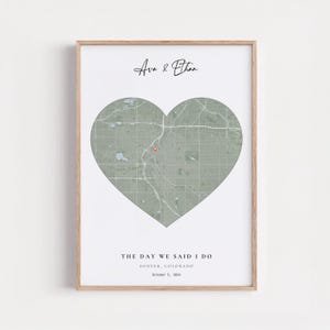 May include: A framed print featuring a heart-shaped map of Denver, Colorado. The map is in shades of green and gray, with a red marker indicating a specific location. The text "Ava & Ethan" is at the top, with "THE DAY WE SAID I DO" and the date below.
