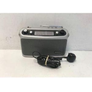 May include: A silver and dark grey portable radio with a telescopic aerial. The radio features control knobs and the brand name "Roberts". A black power cable is connected to the radio, with a black plug.