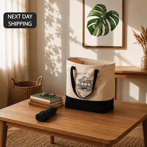 a wooden coffee table with a tote bag, a stack of books, a folded blue shirt, and a framed plant on the wall.