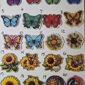 May include: A collection of twenty decorative stickers arranged in a grid, featuring various butterfly designs in purple, orange, green, blue, and red, alongside sunflower illustrations and celestial sun and moon motifs with numbered labels.