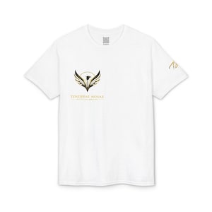 May include: White t-shirt featuring a gold and black phoenix design with the text "TENEBRAE NOVAE" and "relentless ambition". The short-sleeved shirt has a crew neck and a small logo near the collar.