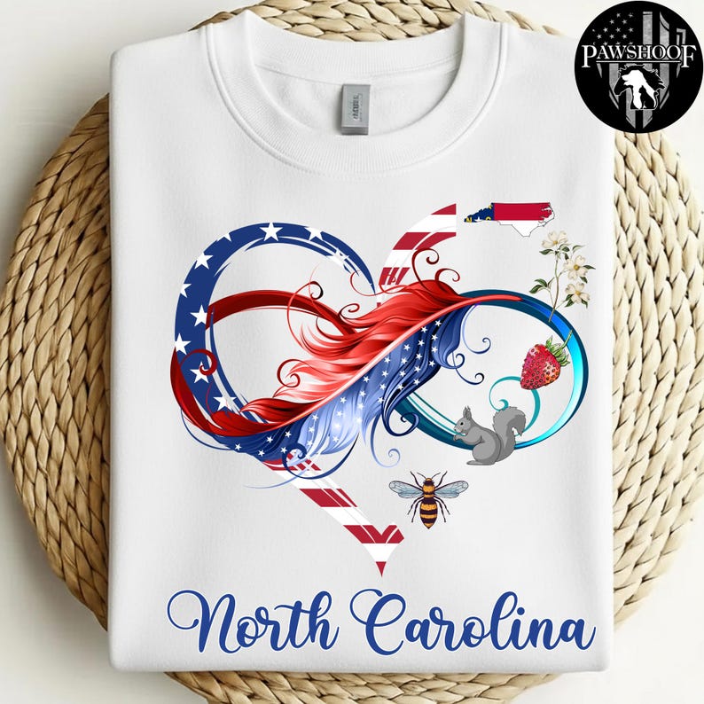 May include: A white sweatshirt featuring a graphic of an infinity heart shape with red, white, and blue patterns. The design includes a North Carolina state outline, a strawberry, a squirrel, a bee, and white flowers. The text North Carolina is below.