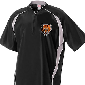 May include: Black short-sleeve athletic shirt with a half-zip closure and a stand-up collar. The shirt features white and gray accents and a tiger head logo on the chest. The shirt has a sporty design.