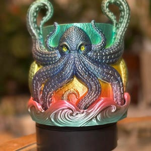May include: A 3D-printed octopus-themed planter. The octopus is primarily blue with yellow eyes, and the planter has a gradient of colors including green, yellow, orange, and pink. The tentacles curve upwards.