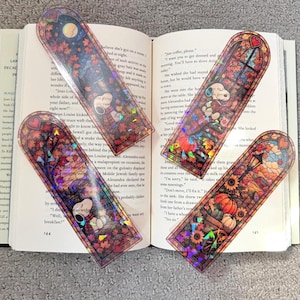 Two holographic autumn bookmarks are arranged on top of the pages of an open book.
