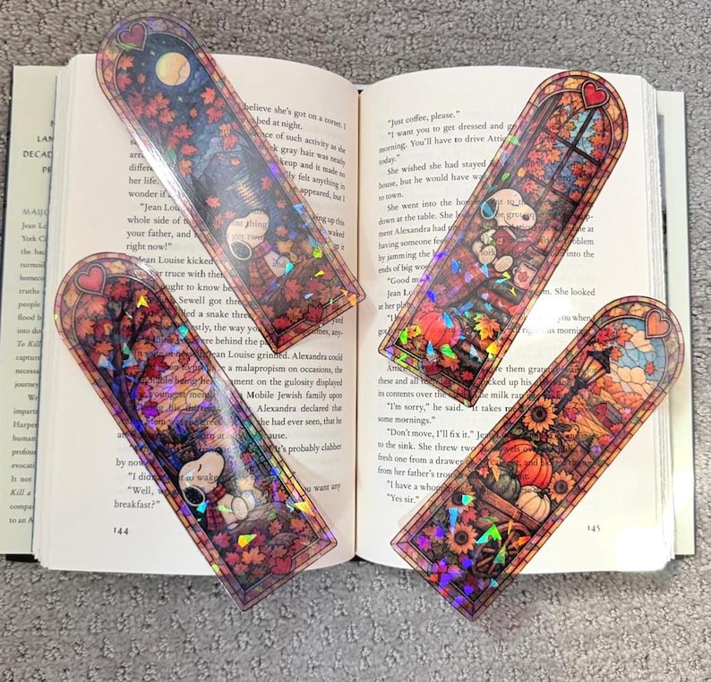 Two holographic autumn bookmarks are arranged on top of the pages of an open book.