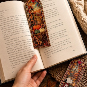 An autumn-themed stained-glass bookmark rests on an open book with another bookmark visible below it.