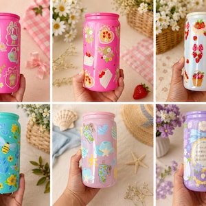 K&ouml;nnte beinhalten: Eine Sammlung farbenfroher, zylindrischer Trinkgef&auml;&szlig;e mit verschiedenen Designs. Die rosa, blauen und lila Becher sind mit floralen, fruchtigen und skurrilen Illustrationen verziert. Jeder Becher wird gehalten, um die Gr&ouml;&szlig;e und das Design des Produkts zu zeigen.