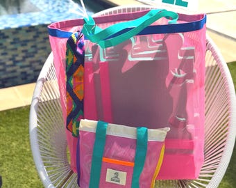 May include: A large pink mesh tote bag and a smaller matching pink mesh pouch with teal straps and an orange accent strip. The pouch features a white label with black text. The text FLOATING BUNDLE is displayed in large teal letters above the bags.