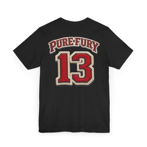 May include: Black t-shirt featuring the text "PURE FURY" above the number "13" in a red and cream-coloured design. The shirt has a classic crew neck.
