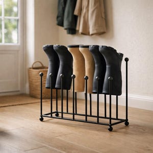 Puede incluir: Un estante de metal negro para botas que sostiene varios pares de botas negras y beige. El estante tiene una base rectangular con soportes verticales y una parte superior redondeada. Las botas están ordenadas, ofreciendo una solución de almacenamiento práctica.