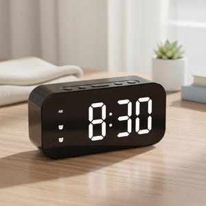 May include: A black digital alarm clock displaying 8:30 AM with bright white numerals. The clock has several buttons on top and two indicator lights on the front. The clock is on a wooden surface.