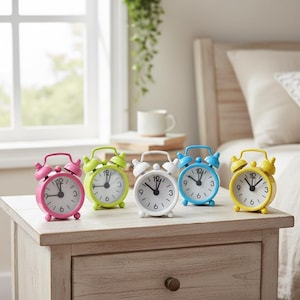 Könnte beinhalten: Fünf kleine, farbenfrohe Wecker in Rosa, Grün, Weiß, Blau und Gelb stehen auf einem hellen Nachttisch aus Holz. Jede Uhr hat ein rundes Zifferblatt mit schwarzen Zahlen und Zeigern sowie eine Metallglocke.