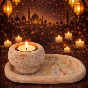 Puede incluir: Un portavelas de piedra con una vela encendida, colocado sobre una bandeja a juego. El fondo presenta una silueta de ciudad, faroles, estrellas y una luna creciente, creando un ambiente c&aacute;lido.