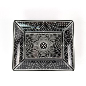 May include: Rectangular black and white decorative tray. The tray features a repeating scale-like pattern on the outer edges and a spiral design in the center. A circular emblem is in the center of the spiral.