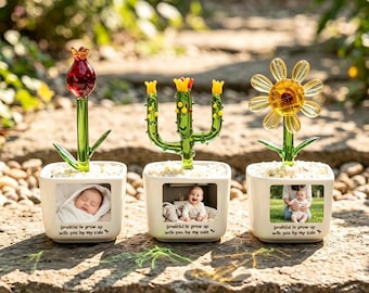 May include: Three white square ceramic planters, each featuring a glass plant sculpture on top and a photo of a baby on the front. The text "grateful to grow up with you by my side" is printed below each photo. The plants are a red tulip, a green cactus, and a yellow daisy.