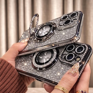 May include: Two silver glitter phone cases with a ring holder and camera lens protector. The cases are encrusted with rhinestones and have a metallic silver finish. The cases are designed to protect the phone and add a touch of glamour.