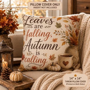 May include: A square throw pillow cover measuring 36 cm by 36 cm, featuring the text Leaves are falling, Autumn is calling. The design includes illustrations of autumn leaves, a ceramic mug with a heart, and a pumpkin on a cream background.