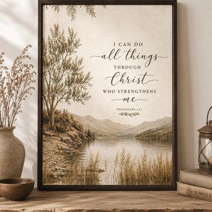 May include: A framed wall art print featuring a landscape of a lake, mountains, and a tree with the text I CAN DO all things THROUGH Christ WHO STRENGTHENS me PHILIPPIANS 4:13 in a mix of serif and script fonts on a light beige background.
