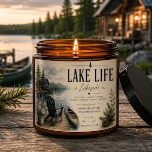 Peut inclure: Une bougie allumée dans un pot en verre ambré avec un couvercle noir. L'étiquette présente une scène de lac avec une chaise, un canoë et le texte LAKE LIFE, Lakeside, fresh citrus, lavender, jasmine, rosemary, cedarwood, oakmoss, patchouli, 255 g.