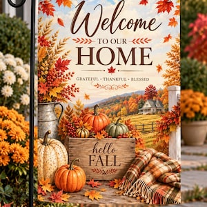 May include: A rectangular garden flag featuring autumn imagery with orange, red, and yellow maple leaves. Text reads Welcome TO OUR HOME, GRATEFUL THANKFUL BLESSED, and hello FALL. The scene includes pumpkins, a wooden crate, and a plaid blanket.