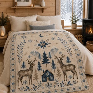 Könnte beinhalten: Eine cremefarbene Fleecedecke mit einer Winterszene, die zwei Hirsche, eine kleine blaue Hütte, Tannenbäume und schneebedeckte Berge zeigt. Das Design umfasst blaue Schneeflocken, Sterne, eine Mondsichel und eine dekorative blaue Bordüre.