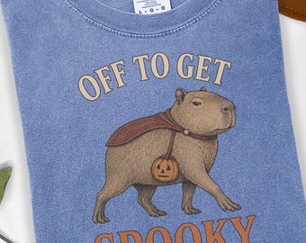 Maglietta con stampa di capibara in stile vintage e colori comodi per Halloween, maglietta con grafica di mantello da vampiro "Off to Get Spooky"