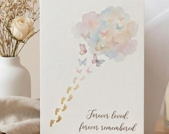 May include: A white greeting card featuring a watercolour illustration of a pastel cloud with butterflies and a trail of small golden baby footprints. The text on the card reads, "Forever loved, forever remembered." The card is displayed with a white envelope.