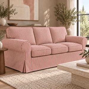 May include: A three-cushion sofa upholstered in a red and white vertical striped fabric. The sofa features rolled arms, a skirted base, and three matching back cushions. The design includes piping along the edges of the cushions and arms.