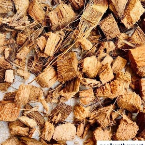 Può includere: Primo piano di un mucchio di pezzi di fibra di cocco marrone. I pezzi di fibra di cocco sono di varie forme e dimensioni, con una consistenza ruvida e fibrosa. Alcuni pezzi hanno fili visibili di fibra di cocco. L'immagine è ben illuminata.