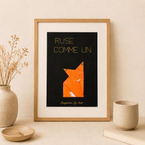 Peut inclure: Une affiche encadrée sur fond noir avec le texte doré RUSE COMME UN au-dessus d'une illustration de renard en origami orange et le texte Benjamin By Clemb en bas. Le cadre est en bois clair et l'affiche est centrée sur une surface neutre.