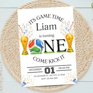 May include: A rectangular birthday invitation card featuring the text ITS GAME TIME Liam is turning ONE COME KICK IT. The design includes two gold trophy illustrations, a colorful soccer ball, confetti, and event details for December 01.