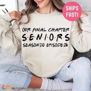 May include: Cream-colored sweatshirt with the text "OUR FINAL CHAPTER SENIORS SEASON:20 EPISODE:26" in black, red, yellow, and blue. The sweatshirt has a crew neck and long sleeves. A pink circle with "SHIPS FAST!" is in the upper right corner.