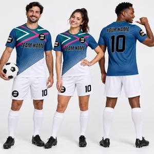 May include: A football kit comprising a blue and white jersey with teal and pink geometric patterns, the text TEAM NAME, and logo spaces. The accompanying white shorts feature the number 10 and a logo, worn with white football socks.