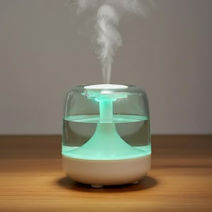 Könnte beinhalten: Ein kleiner, weißer und klarer Diffusor für ätherische Öle mit grünem Licht. Der Diffusor gibt einen Dampfstrahl ab. Der Sockel ist weiß, und die Oberseite ist transparent und zeigt den Wasserstand im Inneren.