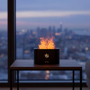 Peut inclure: Un foyer de table noir et cylindrique avec une flamme orange vif. Le foyer a un design minimaliste avec trois lignes courbes sur le devant. Il est posé sur une table en bois avec une vue sur les toits de la ville à travers une fenêtre en arrière-plan.