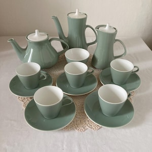 May include: A vintage tea set in a muted green hue, comprising a teapot, a milk jug, a sugar bowl, and six teacups with saucers. The cups and saucers are green, and the teapot, jug, and bowl have white lids.
