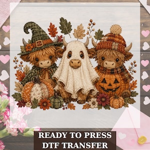 May include: A DTF transfer featuring three Highland cows with autumn themes. One wears a green witch hat, one is draped in a white ghost sheet, and one wears a plaid beanie. They are surrounded by pumpkins, fall leaves, and flowers.