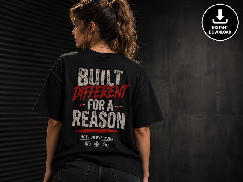 May include: A black short-sleeve t-shirt featuring the white and red distressed text BUILT DIFFERENT FOR A REASON, with the smaller text NOT FOR EVERYONE and three circular icons below, all printed on the back of the garment.