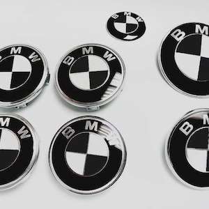Könnte beinhalten: Eine Sammlung von BMW-Emblemen in verschiedenen Größen. Die Embleme zeigen das BMW-Logo, einen schwarz-weiß geviertelten Kreis in einem schwarzen Ring, mit den Buchstaben "BMW" am Rand. Auf weißem Hintergrund.