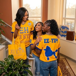 May include: Three gold V-neck jerseys with blue trim and blue lettering. The jerseys feature Greek letters, the text EE-YIP!, and a blue poodle graphic. A matching gold canvas tote bag with the text XI ETA EST. 1994 and a heart-shaped keychain is included.