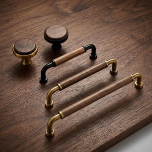 May include: A collection of cabinet hardware including two round knobs and three bar pulls. The knobs feature circular wood inserts with brass or black metal bases. The bar pulls consist of cylindrical wood handles with brass or black metal ends.