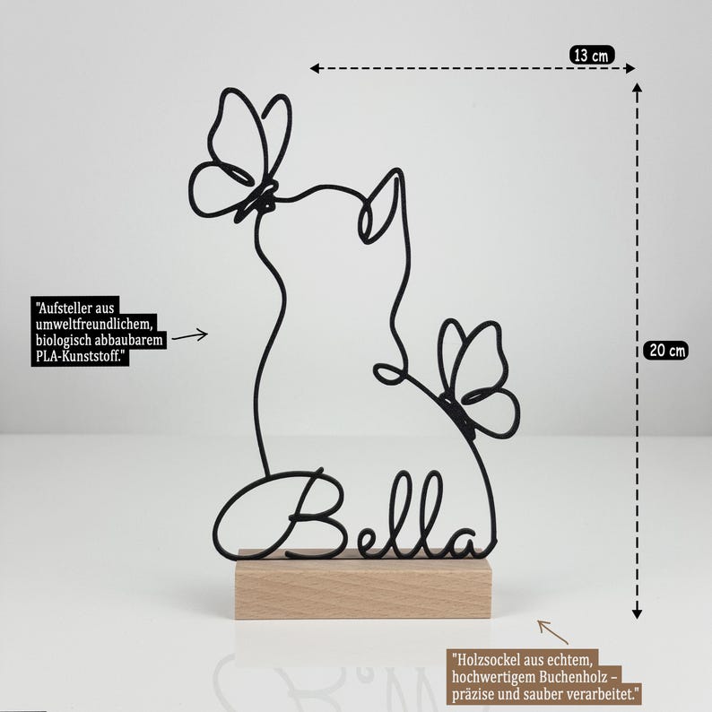 May include: A black wire sculpture of a cat with two butterflies and the name Bella, mounted on a rectangular wooden base. The sculpture measures 13 cm in width and 20 cm in height. The text indicates it is made of biodegradable PLA plastic.