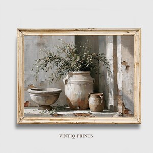 Könnte beinhalten: Ein gerahmter Kunstdruck mit dem Titel VINTIQ PRINTS, der ein Ölgemälde einer großen beigen Keramikurne mit Olivenzweigen, einer passenden beigen Fußschale und einem kleineren beigen Krug vor einer verwitterten Steinmauer zeigt.