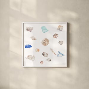 May include: A square white framed wall art print featuring a watercolor illustration of various seashells, sea glass in blue and turquoise, and a small crab scattered across a plain white background, creating a collection of coastal elements.