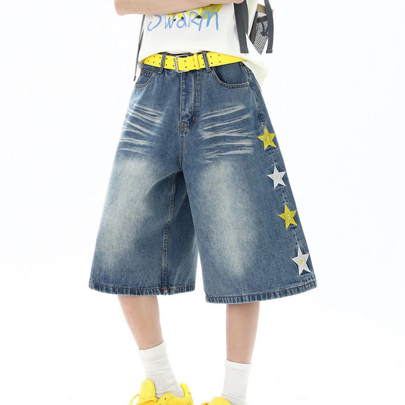 May include: Blue denim culottes with star accents. The wide-leg shorts feature a yellow belt and white socks. The text on the shirt says "warm".