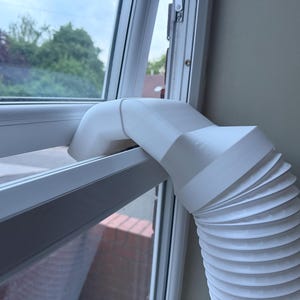 May include: A white plastic window vent adapter for a portable air conditioner hose. The adapter features a curved, rigid nozzle that fits into a window frame, connected to a flexible, ribbed, accordion-style exhaust hose for air ventilation.