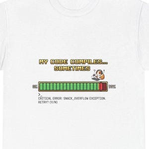 May include: White t-shirt featuring the text "MY CODE COMPILES... SOMETIMES" in a retro pixelated style. The design includes a progress bar graphic with an error message and a question mark.