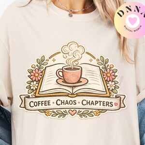 Op de afbeelding: Crèmekleurig T-shirt met een afbeelding van een open boek en een kopje koffie, omringd door bloemen. De tekst "COFFEE • CHAOS • CHAPTERS" staat op een banner onder het boek. Het shirt heeft een relaxte pasvorm.